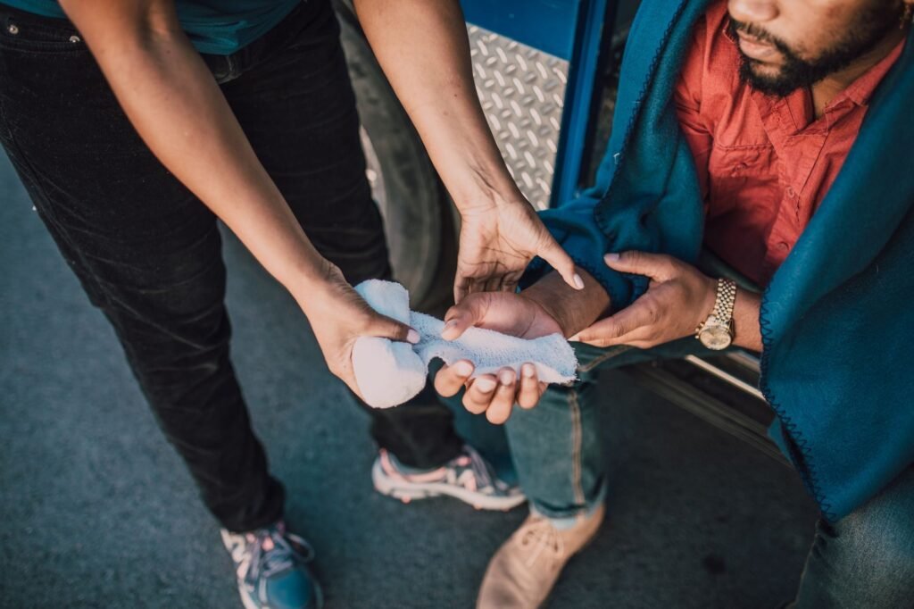 Close-up of a person applying gauze to an injured hand, highlighting first aid care.